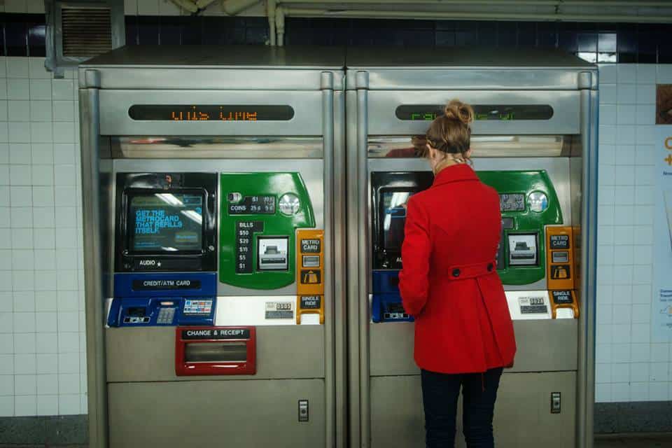 woman in red getting a subway ticket in NYC
