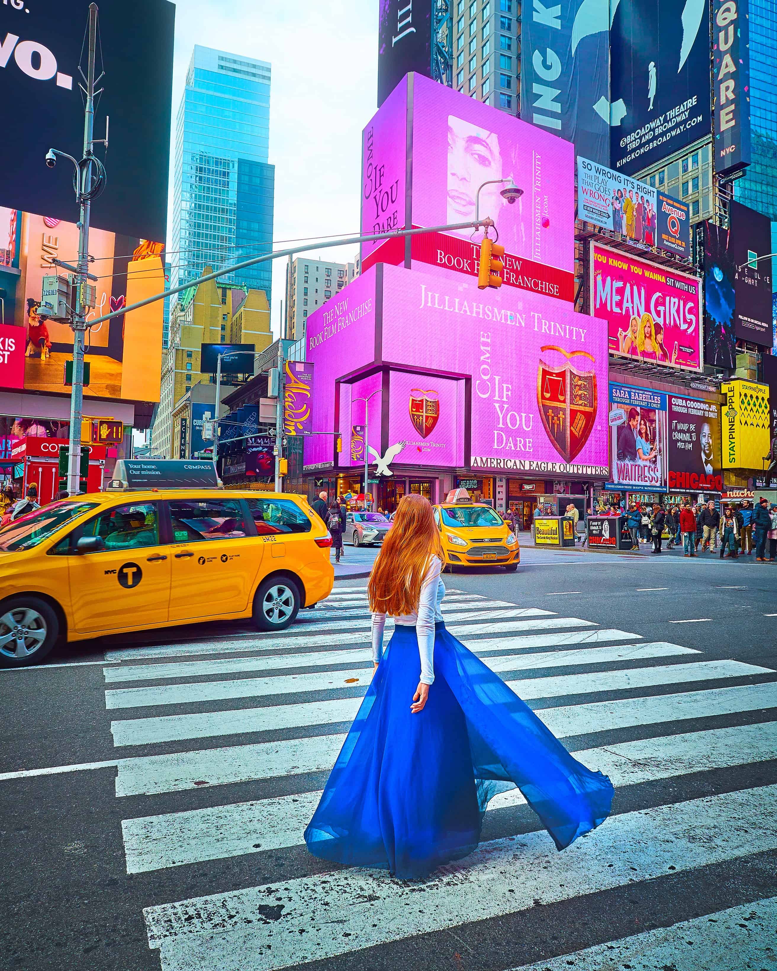 woman walking across a road in time square wearing a blue skirt
