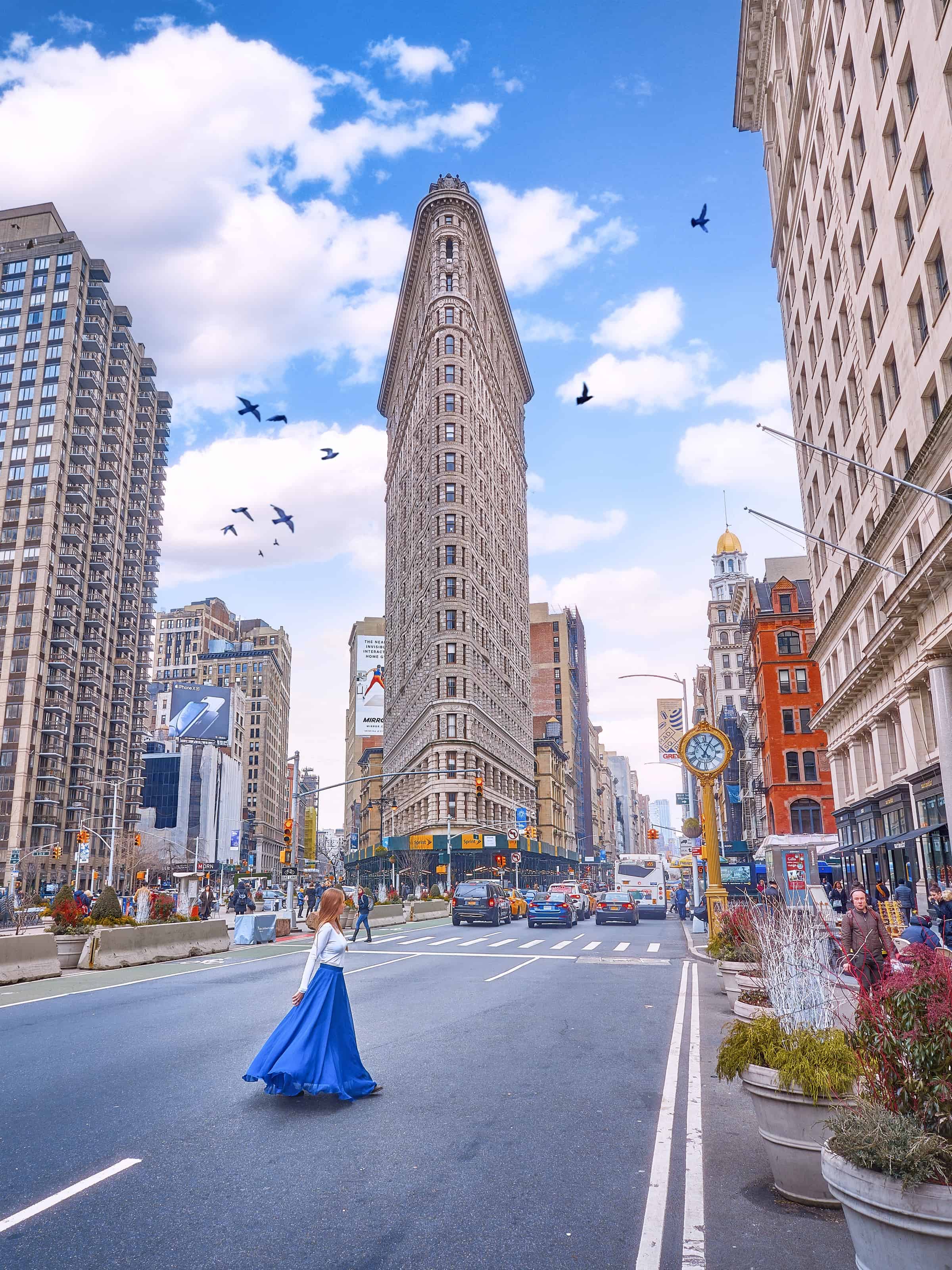 woman standing in the road in NYC crossing past the flat iron building in midtown manhattan 