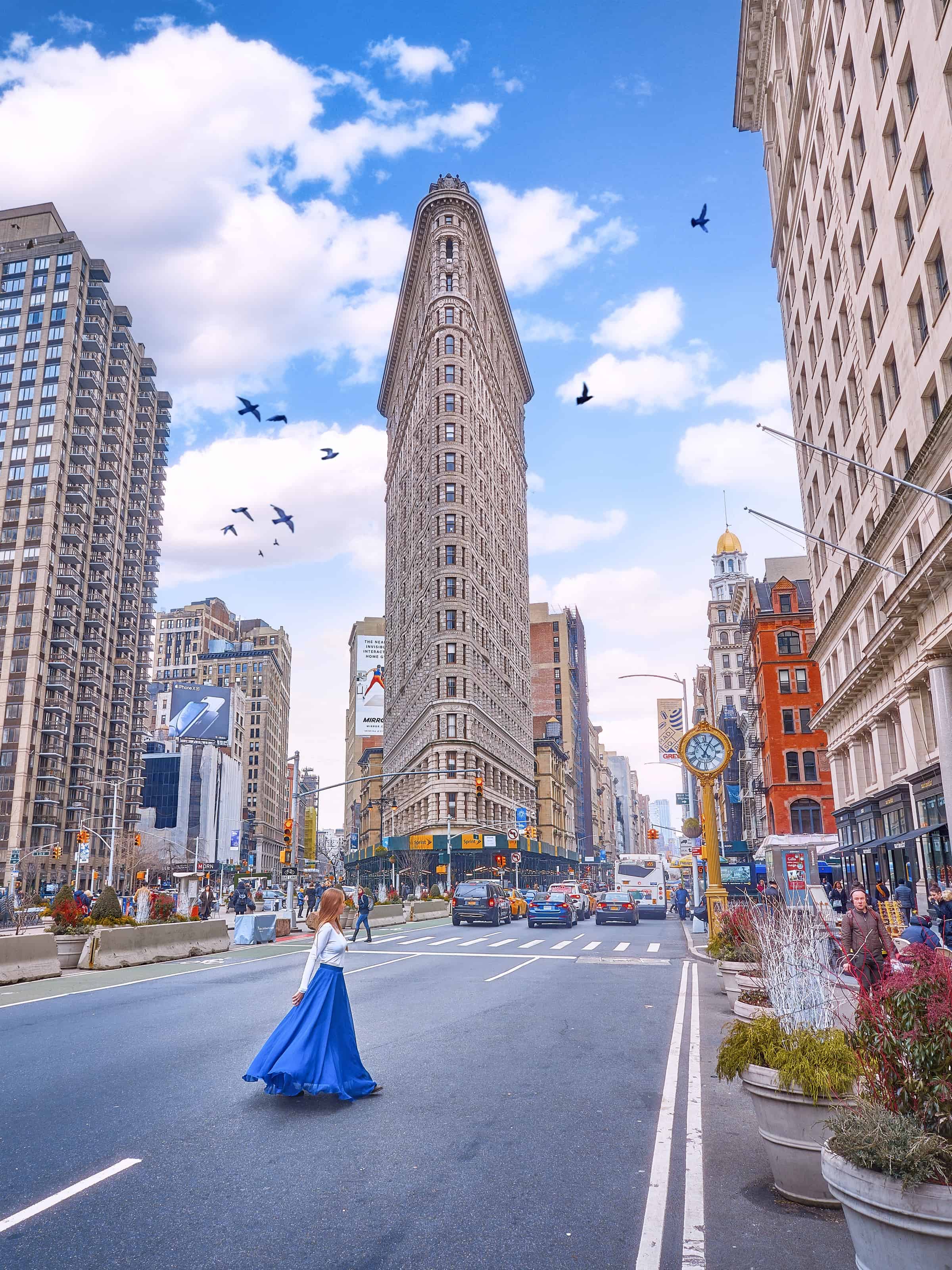 woman standing in the road in NYC crossing past the flat iron building in midtown manhattan
