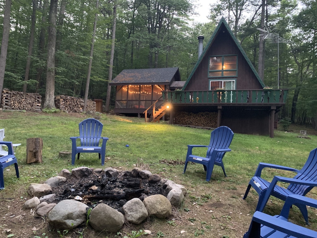 view of the fireput and A frame with screened in porch and twinkle lights nearby