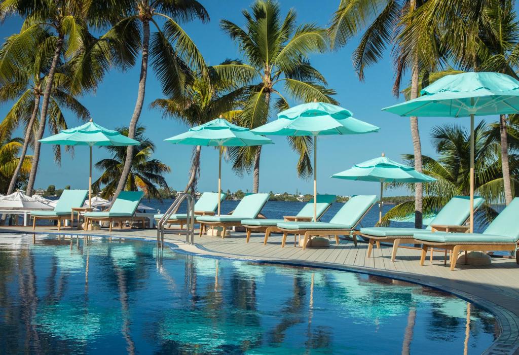 Pool at one of the  all-inclusive resorts in the south with blue lougers and umberellas and the sea in the background. 