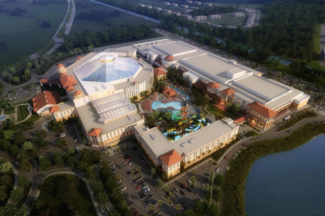 brown building with glass roof surrounding a pool and waterpark area with parking lot