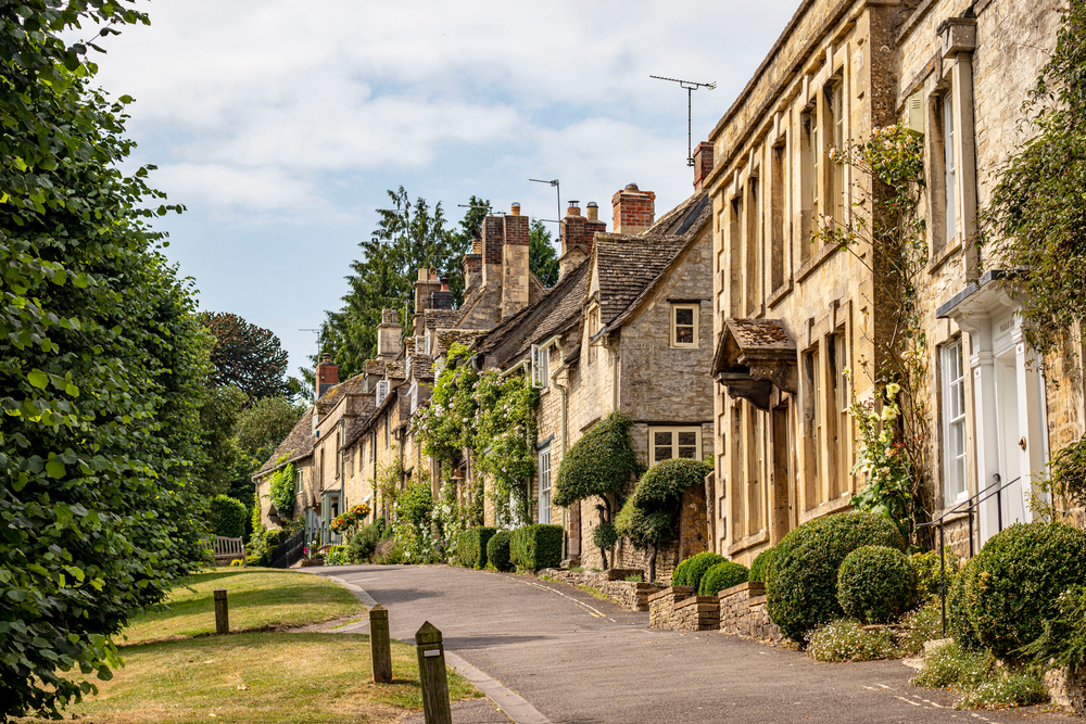 Lovely houses up a street in burford. They are stone houses with plants outside. 