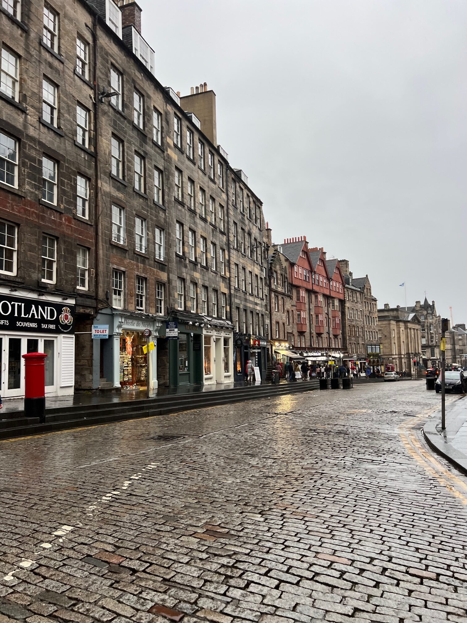 royal mile road in Edinburgh Scotland with shops and brown buildings in the rain