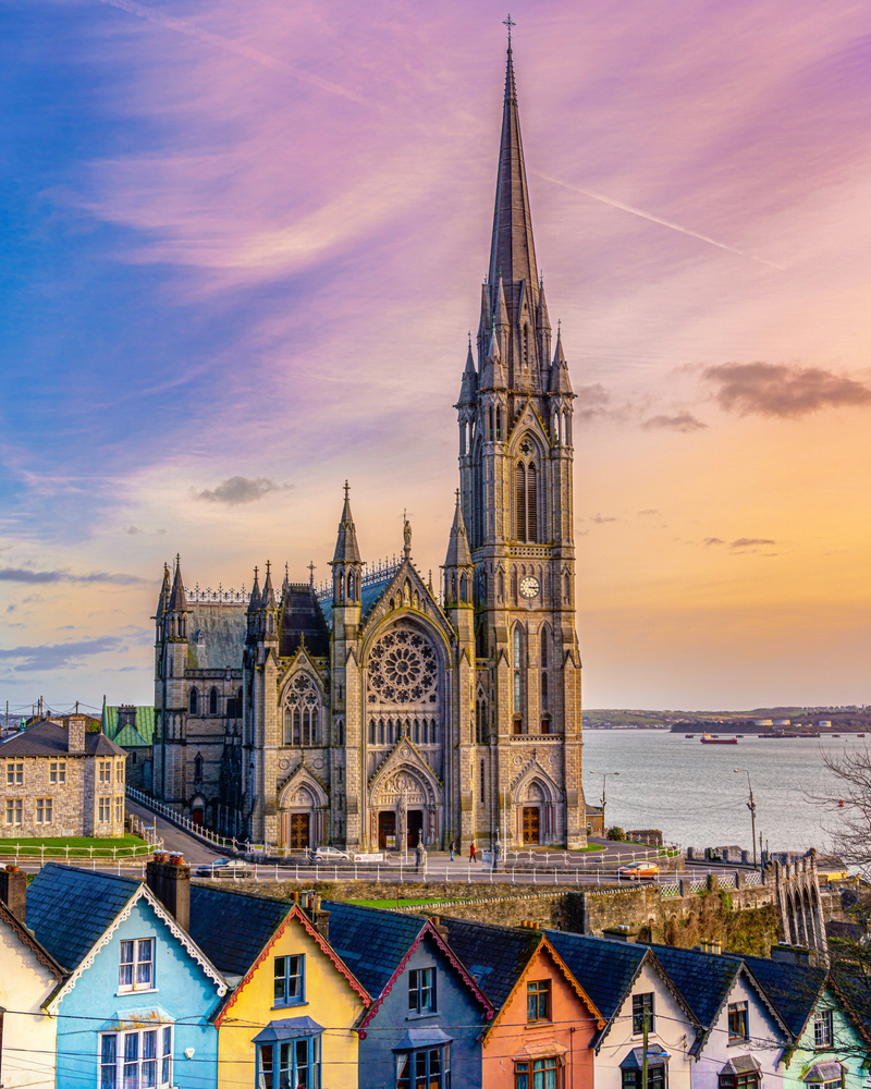 The Cathedral Church of St Colman overlooking the harbor with colorful houses. 