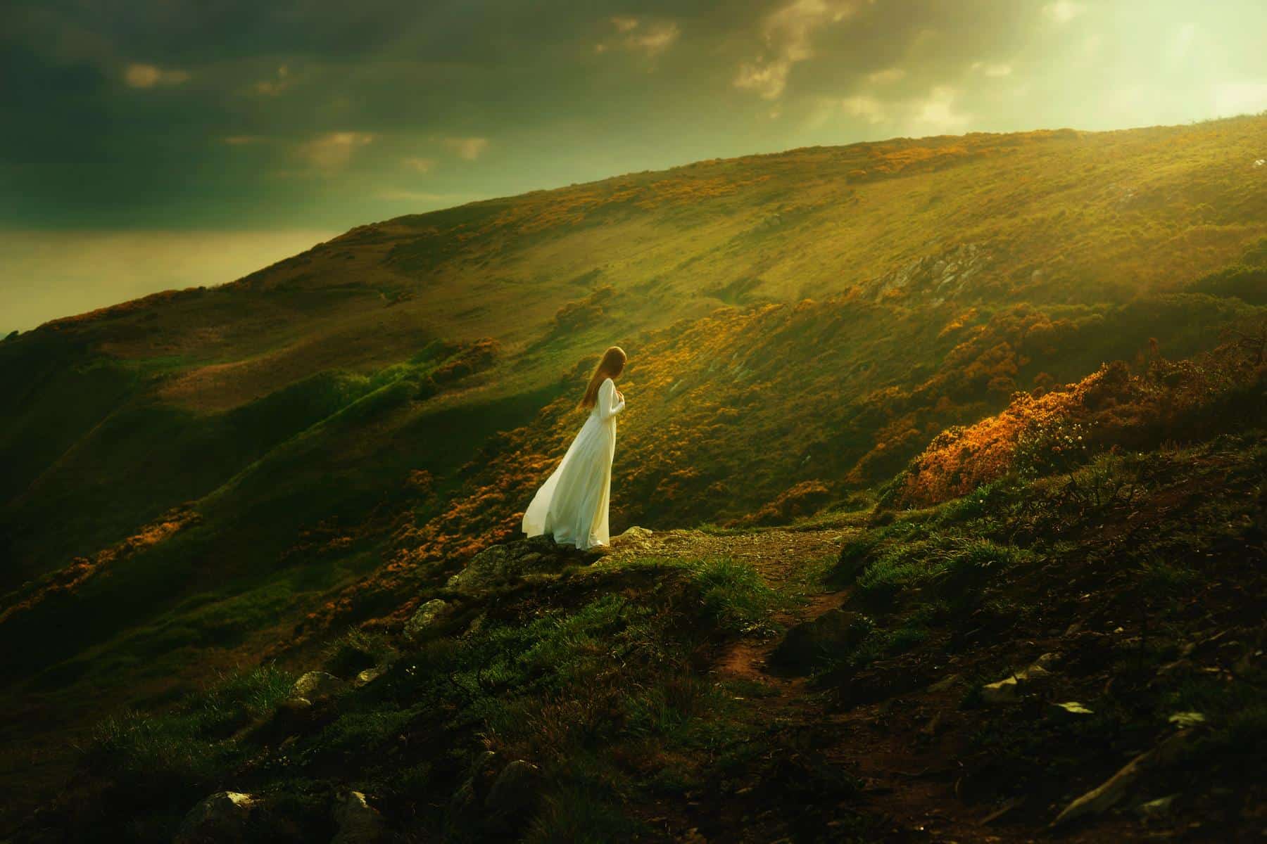 View of Victoria and in a long white dress on the dramatic green and gold cliffs of Howth