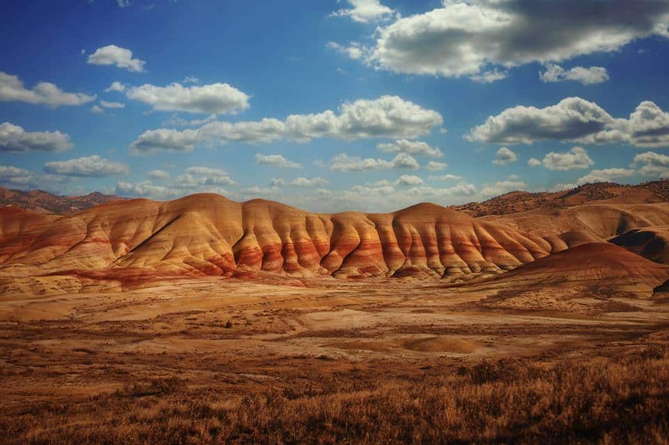 Colorful Painted Hills in Oregon with a sunny blue sky with some clouds.