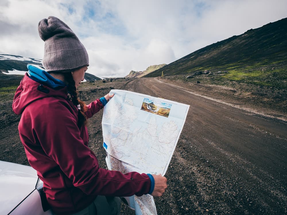 woman with map on side of road while driving in iceland