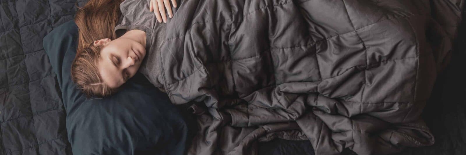 laying down with a weighted blanket in bed | anxiety blanket