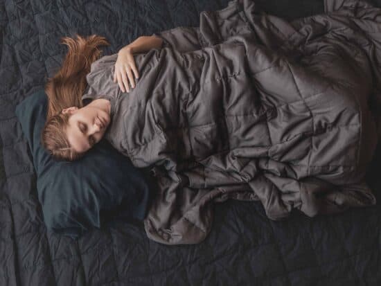 laying down with a weighted blanket in bed | anxiety blanket