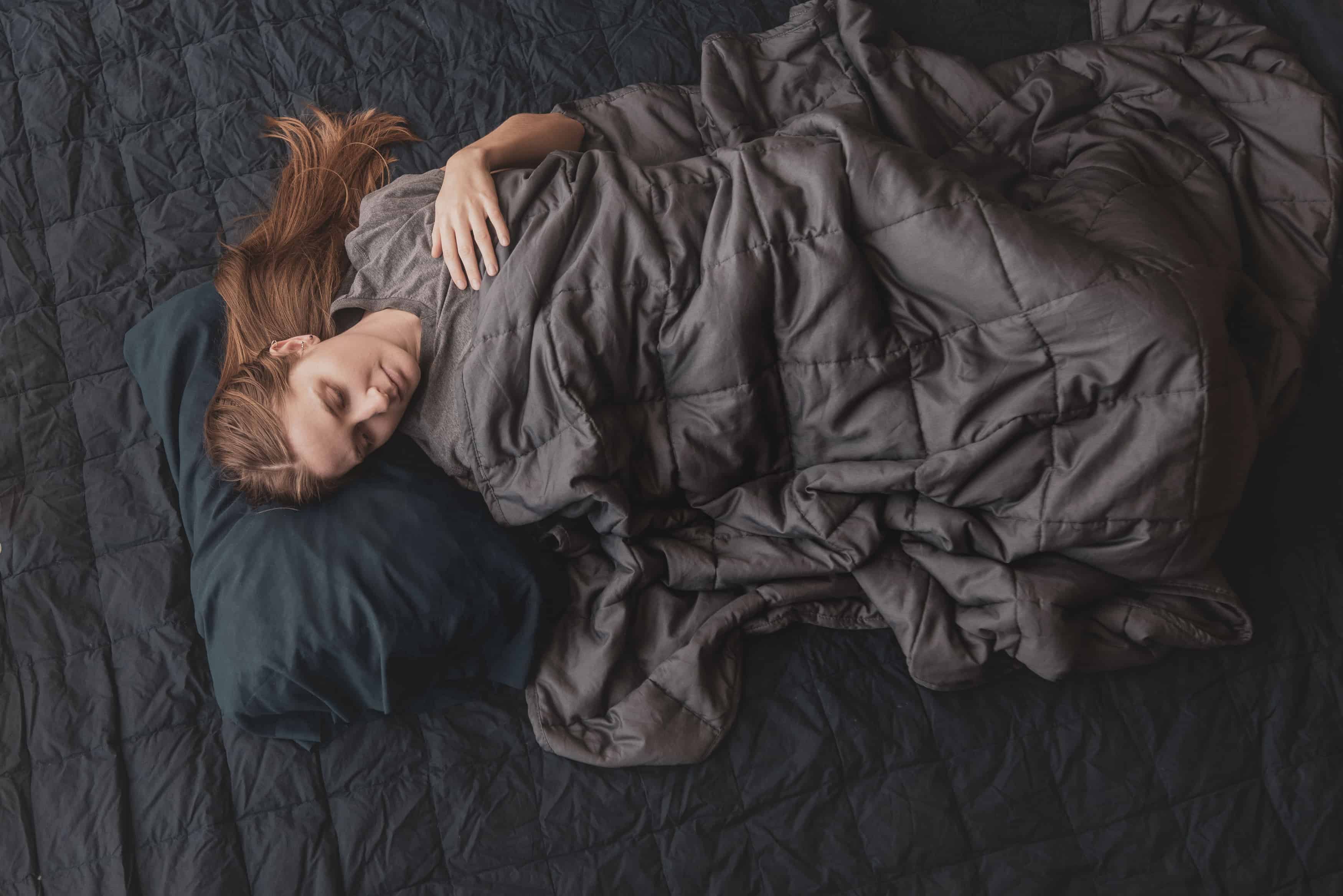 laying down with a weighted blanket in bed | anxiety blanket