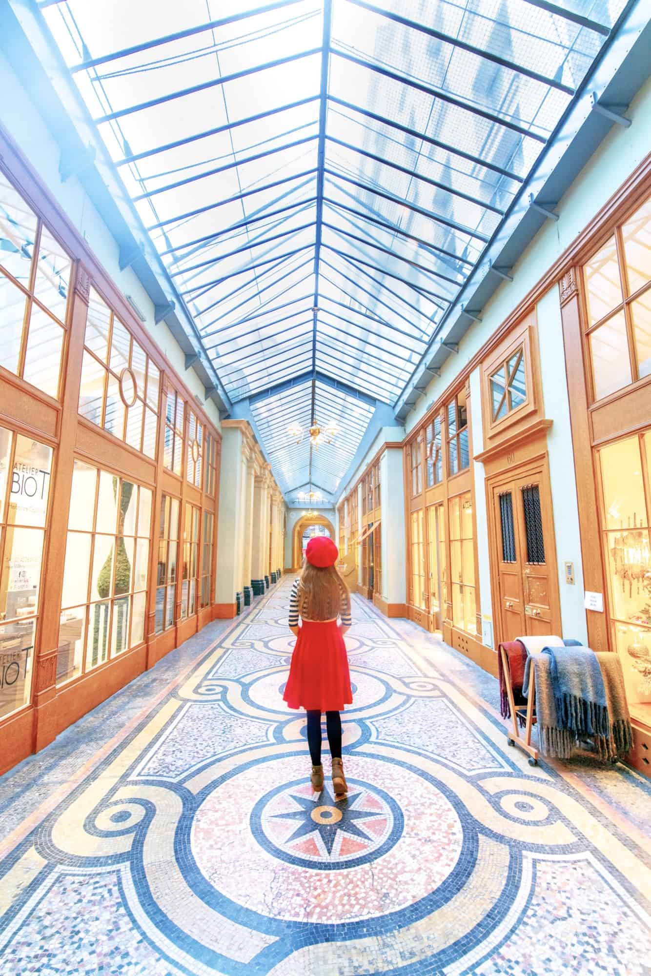 Woman in red skirt and beret standing in the glass covered Galerie Vivienne.