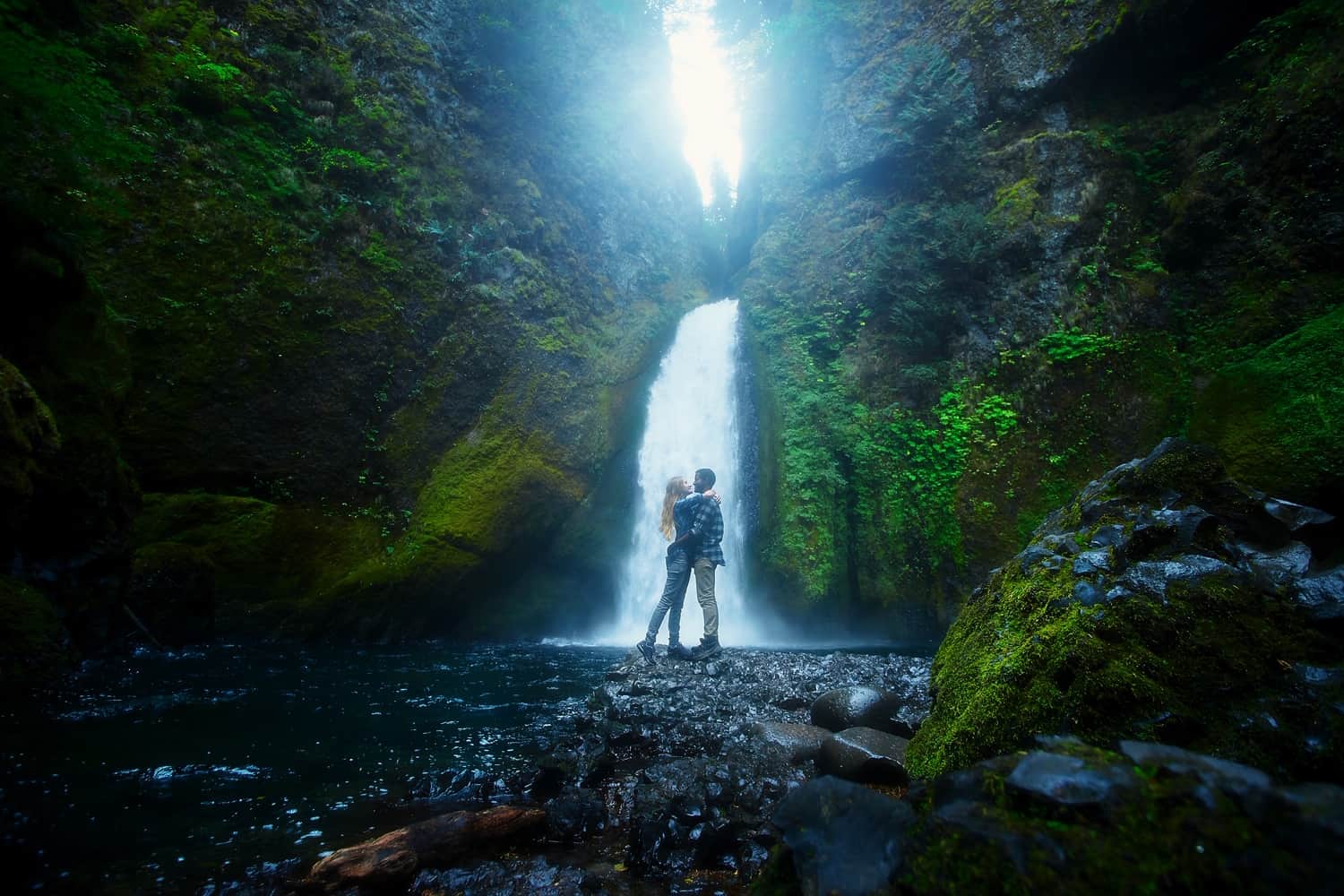 Couple kissing at Wachella Falls in oregon with sun in the background