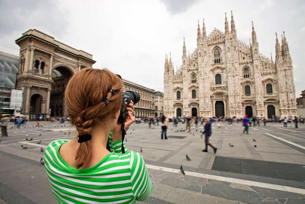 woman taking photos with extra memory cards on her Italy packing list