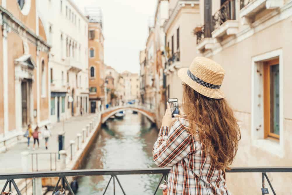 woman charging phone with portable charger on Italy packing list