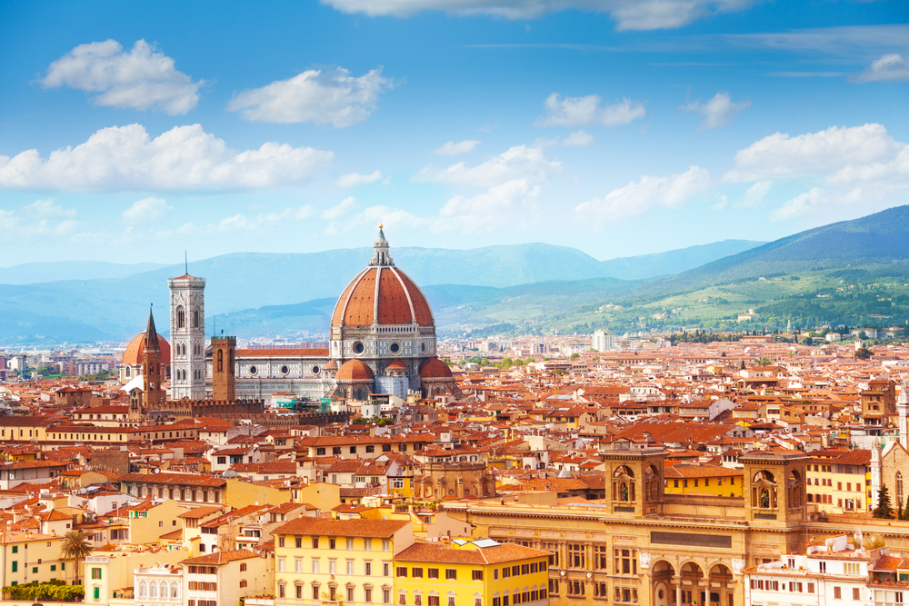 Panorama view over Florence including Duomo and mountains in the background.