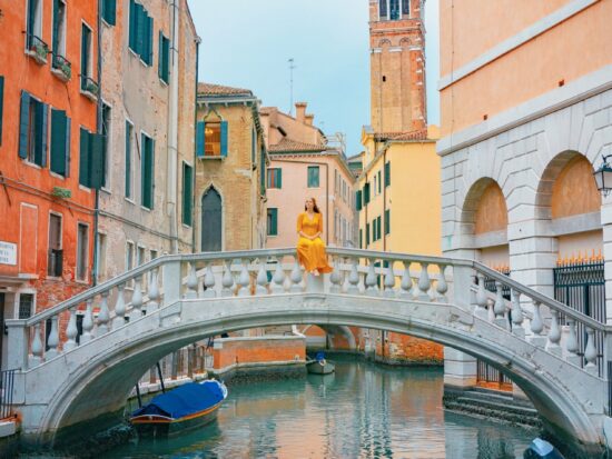 a girl in yellow dress sitting on one of the bridges in Venice
