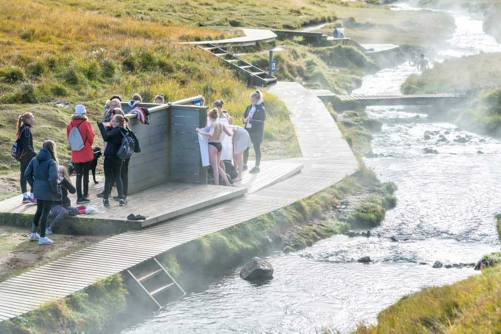 people on wood changing platforms at Reykjadalur Hot Springs