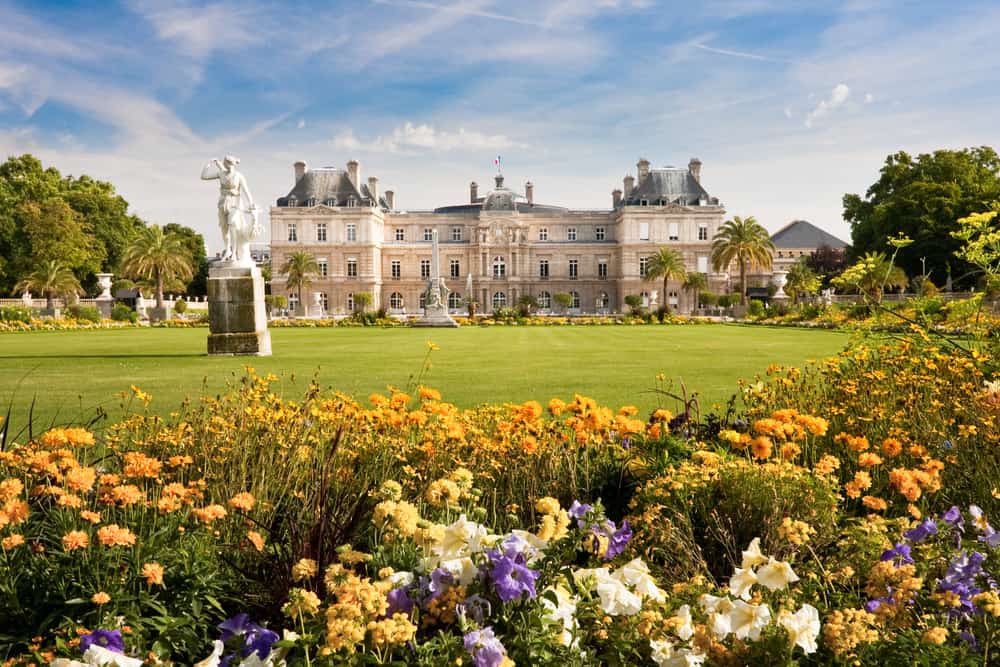 Luxembourg Palace viewed through flowers with statues in Jardin du Luxembourg, a beautiful place in Paris.