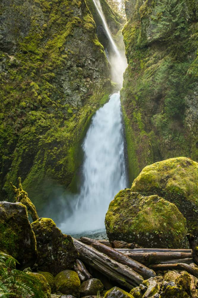  Wahclella Falls in Oregon with greenery around it and sun