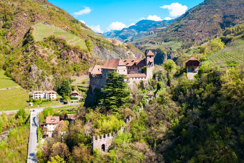 Aerial view of Castel Roncolo near Bolzano in the Dolomites with green trees surrounding it 