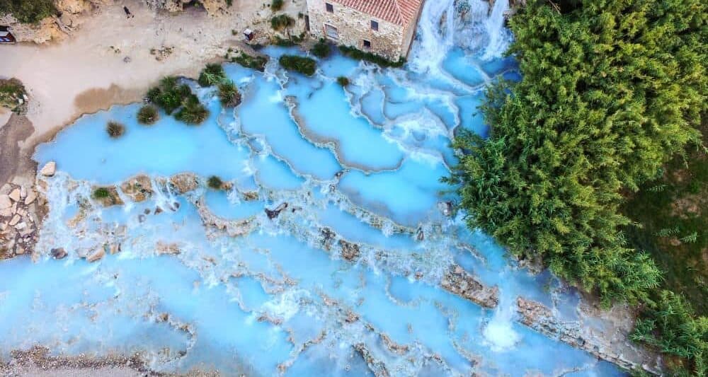 A drone view of the hot springs in Saturnia shows the multiple pools of the thermal springs and the icy blue waters.