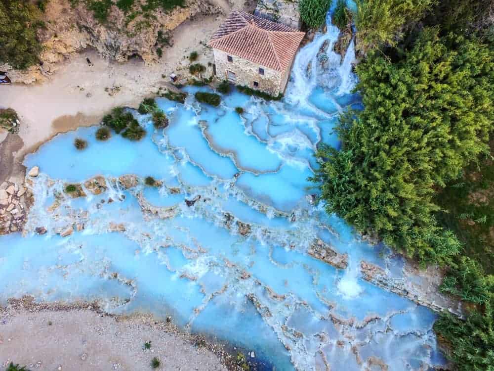 A drone view of the hot springs in Saturnia shows the multiple pools of the thermal springs and the icy blue waters.