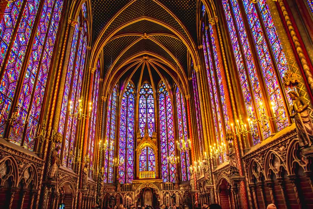 the stained glass walls of St. Chapelle Cathedral lit by candles as well as external light