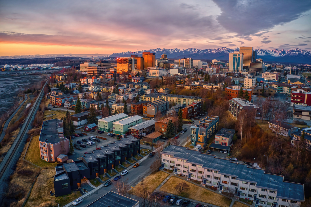 Aerial image of Anchorage at sunset with mountains in the distance.