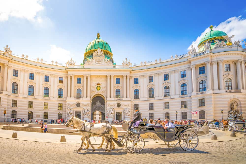 Horse-drawn carriage passing the front of the grand Hofburg Palace in Vienna.