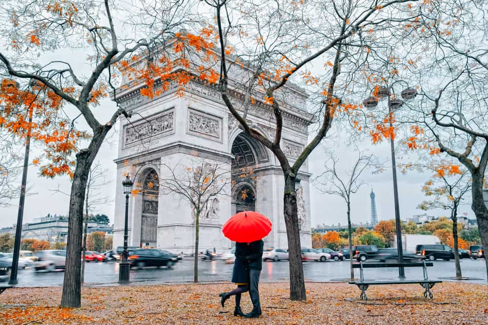 couple kissing by arc de triumph in Paris