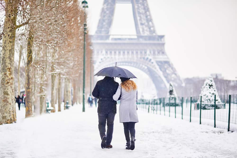couple on their honeymoon in Paris walking in snow