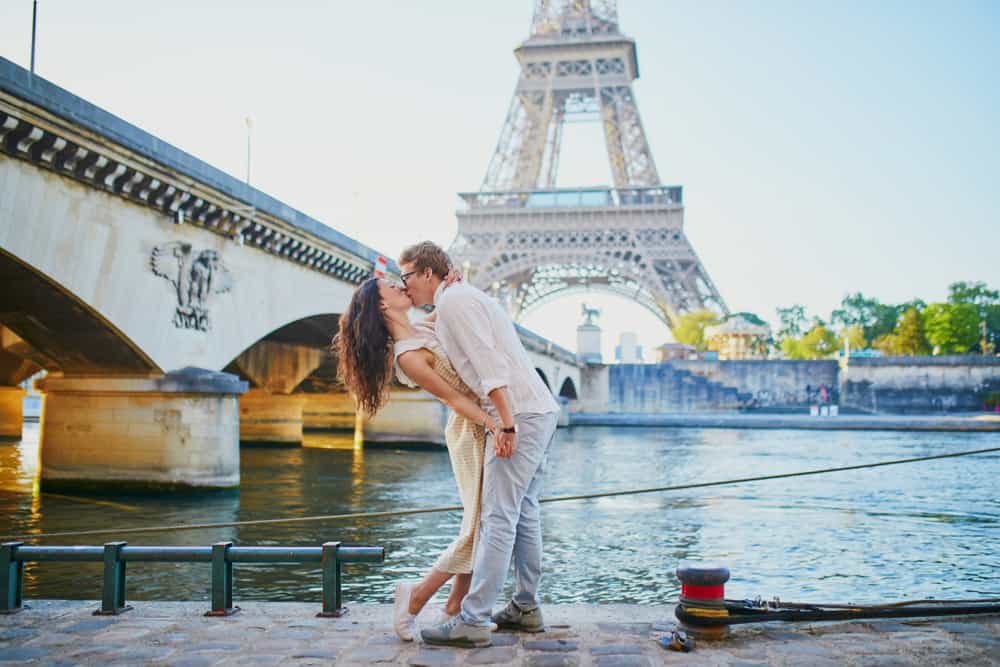 couple kissing in front of the Eiffel Tower on their paris honeymoon