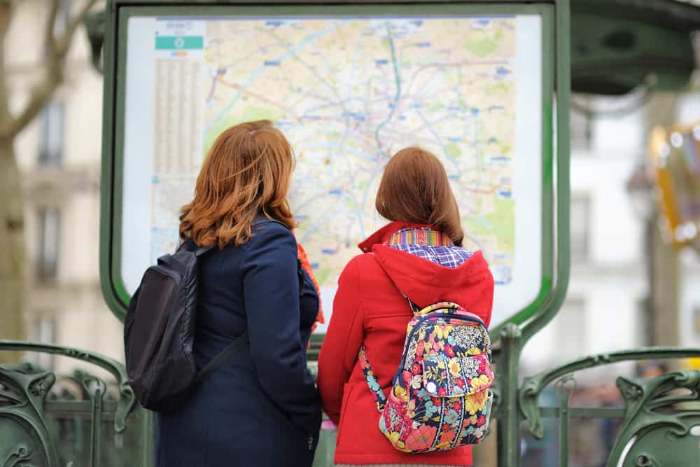 women looking at a map of the paris metro