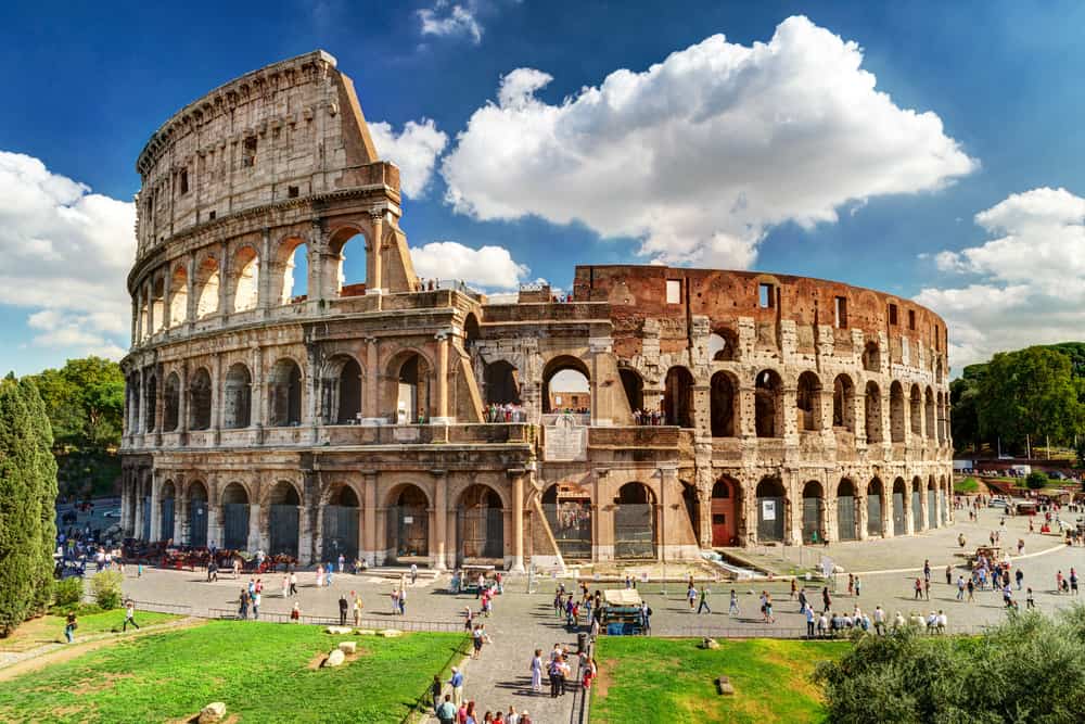 The exterior of the Colosseum in Rome with tourists outside.