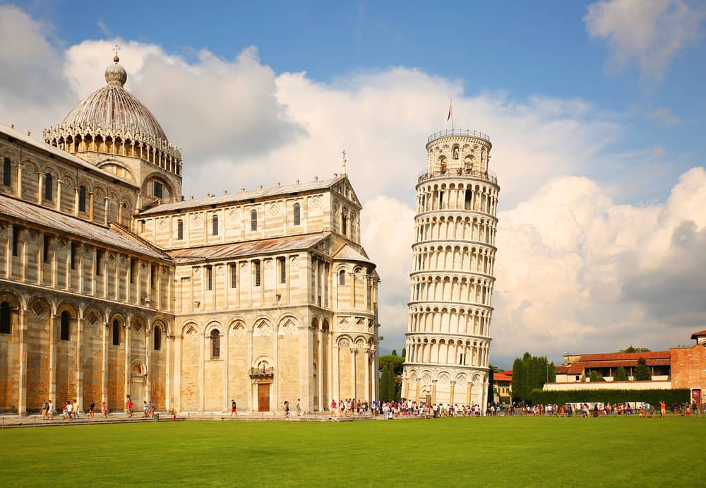 Leaning tower of Pisa tourist attraction in italy with green grass and crowds on a sunny day