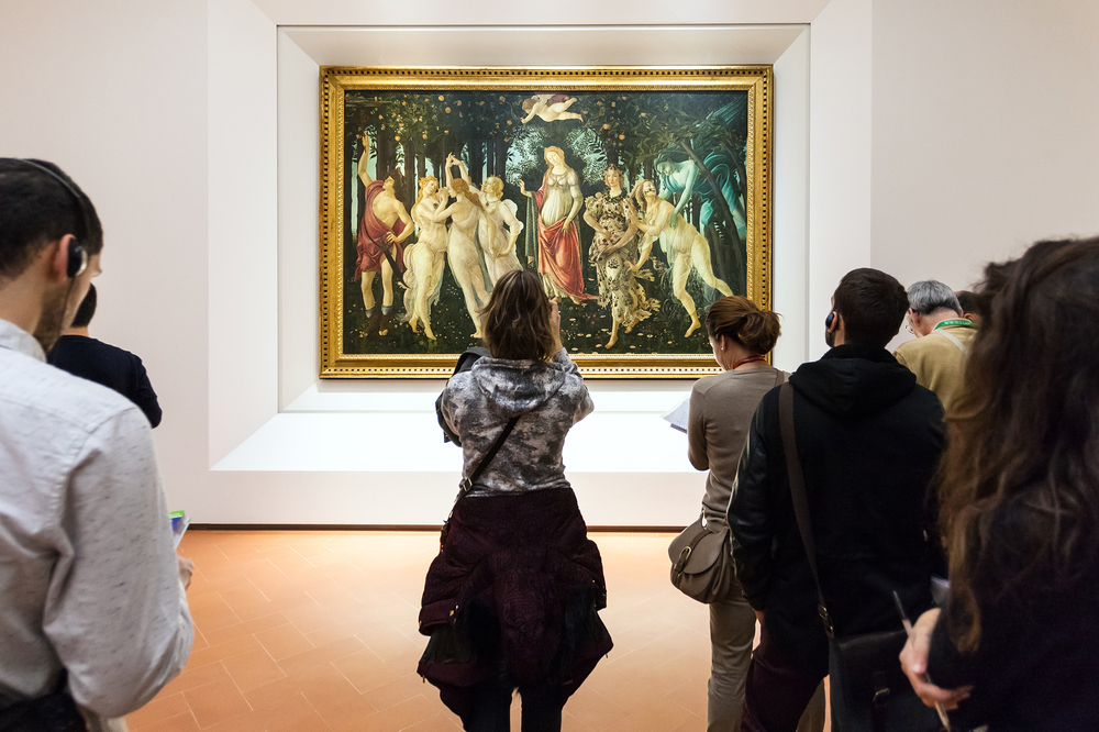 people in a gallery in Florence italy taking photos of a painting