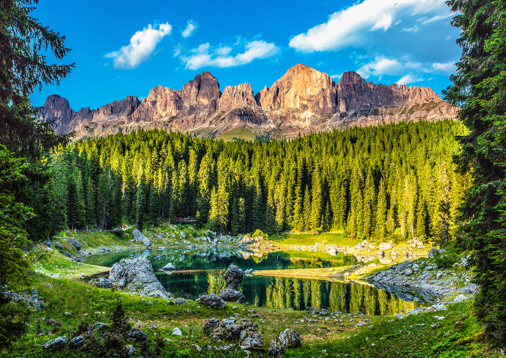 Lake Carezza in the italian dolomites with lake in foreground, mountains in background, and blue sky