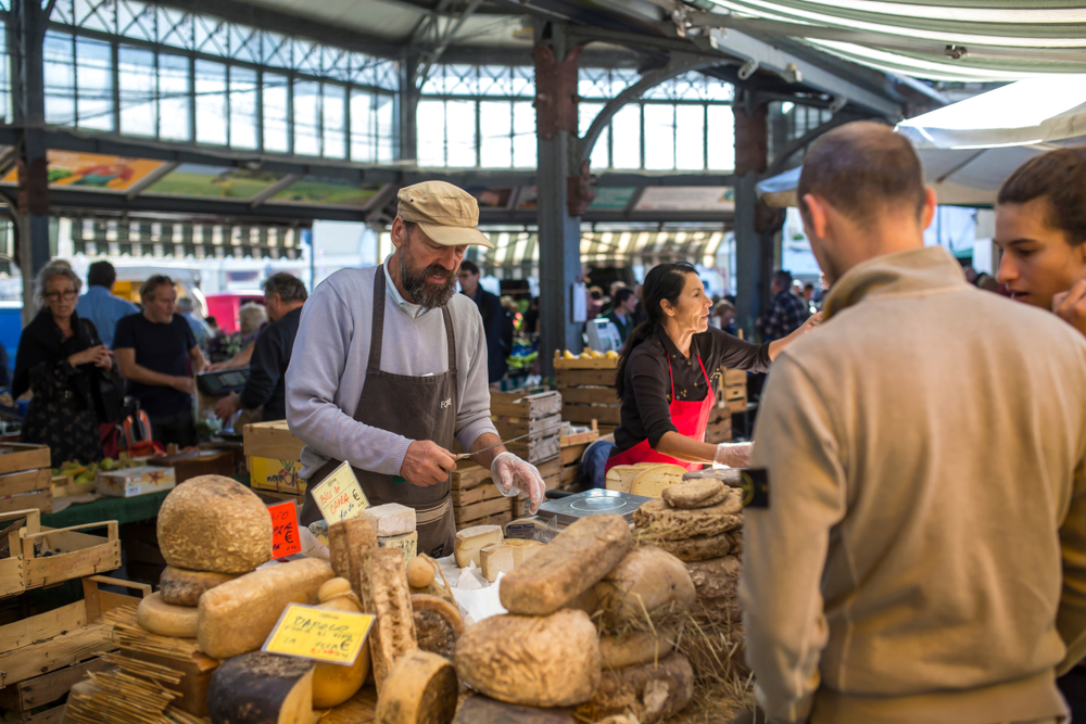 people in Parma Italy shopping for cheese and bread at a market stand 