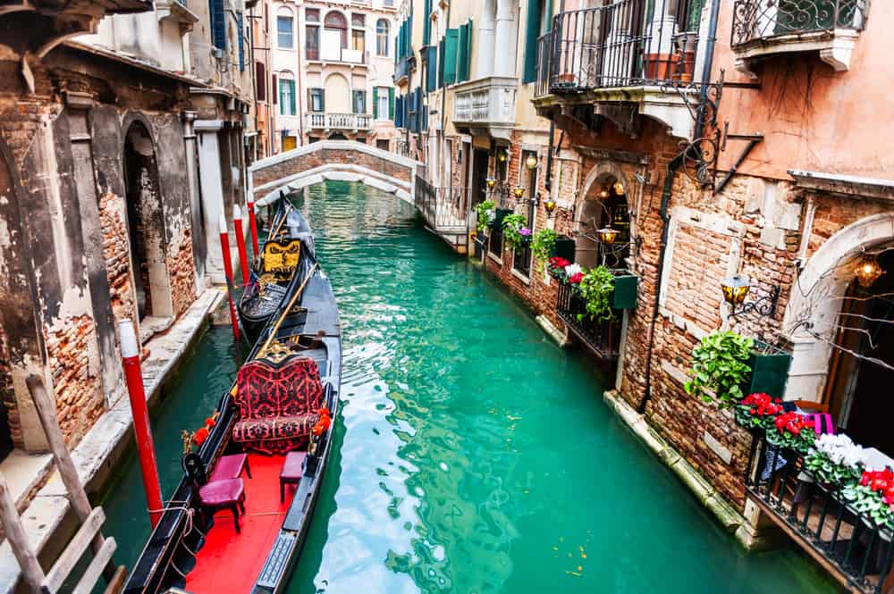 Gondola parked on a canal in venice with flowers all around it showcasing venice as one of the best places to visit in italy