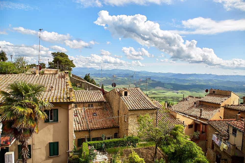 Volterra city view looking into valley with houses in the foreground and green trees