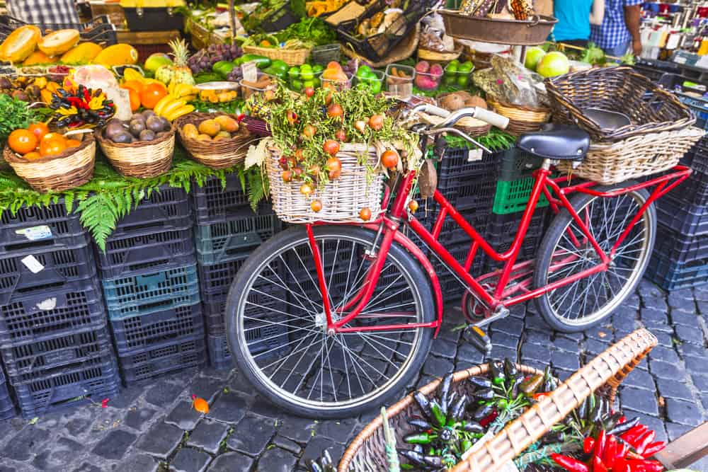 A red bike with baskets next to a food stand at a food market during 4 days in Rome.