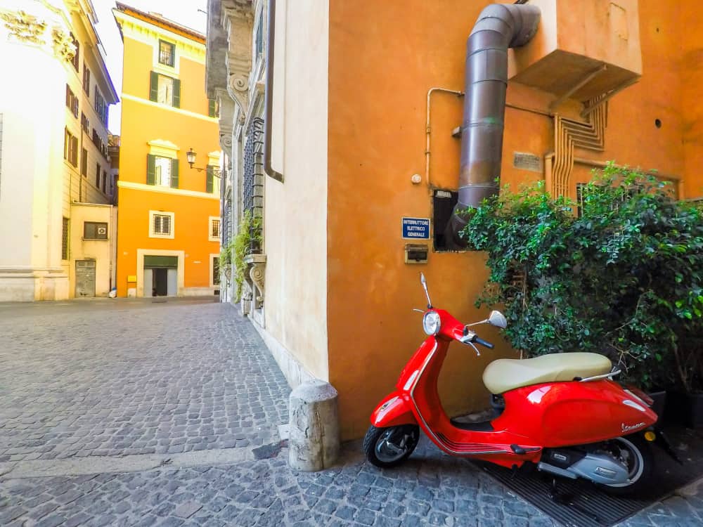 red vespa on an empty street in florence 