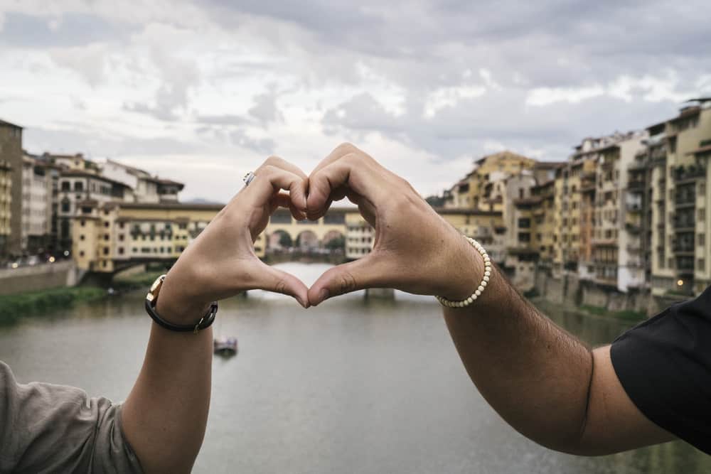 Photo of couple making a heart with their hands.