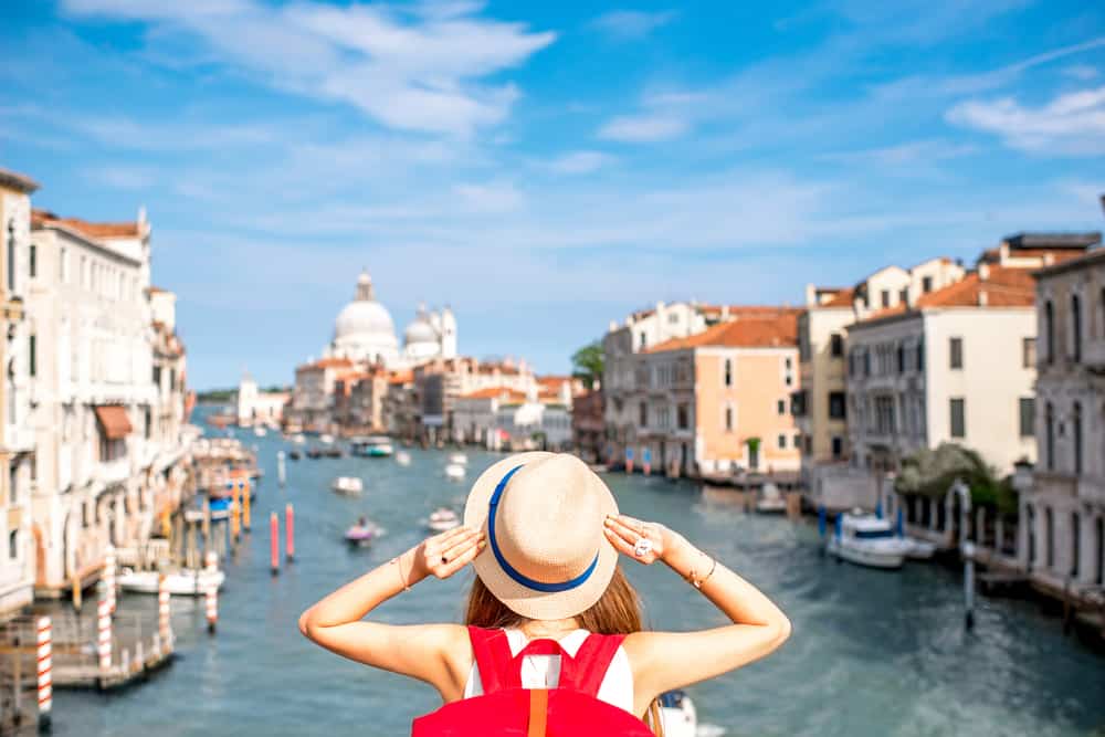 Best Instagrammable places in Venice Italy | woman holding hat over Grand Canal in Venice | prettiest spots in Venice Italy for photos