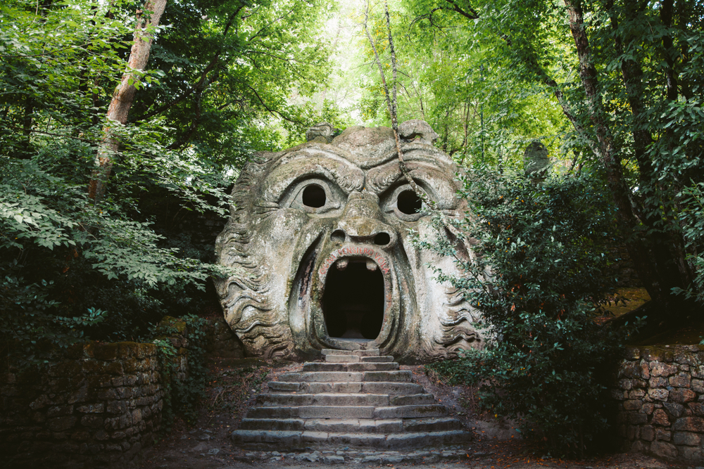 A sculpture of a creepy face with a path leading into its open mount at the Park of the Monsters.