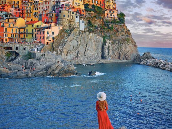 woman in red dress standing in Manarola one of the smaller cities in italy on the riviera