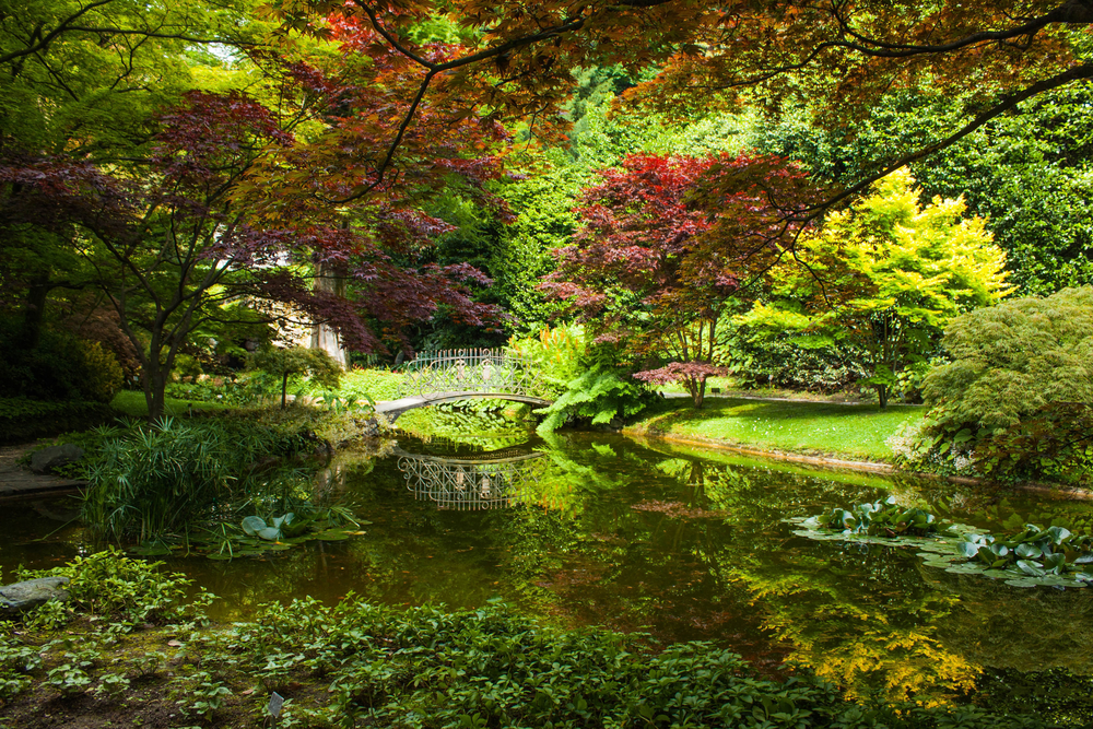 garden with a lake, a white bridge, and red and green trees Northern Italy itinerary