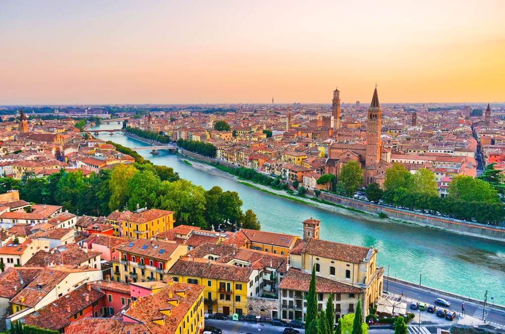 top city in Italy verona at sunset with blue river going through the middle of brown buildings